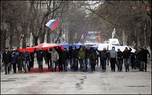 Pro-Russian demonstrators march with a huge Russian flag during a protest in front of a local government building in Simferopol, Crimea, Ukraine today.
