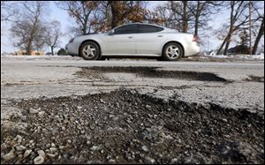 A car passes potholes on Nebraska Avenue near City Park. The city has repaired more than 20,000 potholes so far this season.
