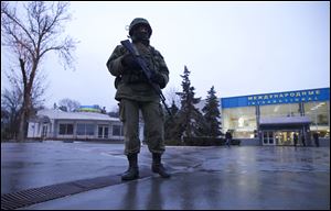 An unidentified armed man patrols a square in front of the airport in Simferopol, Ukraine, today.  Dozens of armed men in military uniforms without markings occupied the airport in the capital of Ukraine's strategic Crimea region.