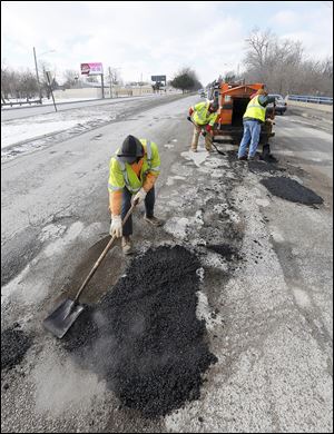 City employees, from left, Bernie Hamilton, Sammie Coleman, Jr., and Jeff Green fill potholes while traffic flies past them Wednesday on Anthony Wayne Trail. Rude, reckless drivers can be a frequent problem for rolling work zones.