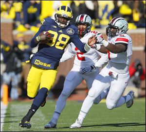 Ohio State defenders Ryan Shazier, center, and Noah Spence chase Michigan quarterback Devin Gardner during their Nov. 30, 2013, game in Ann Arbor. While Ohio State athletic director Gene Smith called reports that the Big Ten is exploring a move toward more Friday night games 