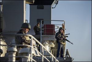 Members of the Ukrainian military stand guard aboard a navy ship in the harbor of Sevastopol in the Crimea region.  Ukrainian officials said Russia demanded the crew switch its allegiance, a claim Russia denies.