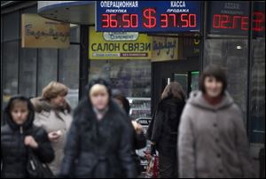 People walk past a currency exchange office in downtown Moscow, Russia, today.