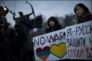Ukrainian Maria, 23, right, and Vanui, 22, hold posters against Russia's military intervention in Crimea, in Kiev, Ukraine, Sunday.