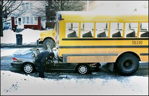 A Toledo police officer examines the wreckage of a Toledo Public Schools bus that was rear-ended while on its way to  Westfield Achievement. The bus was carrying only the driver, a bus aide, and one student. They suffered minor injuries.