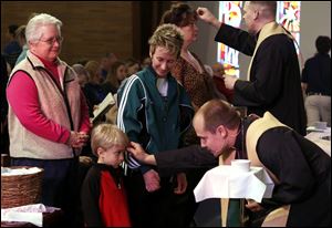 Paula Prediger, of Holland, Ohio, watches her son Kody Prediger, 3.5, receive ashes.