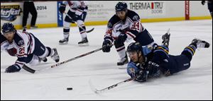 Toledo’s Kevin Lynch slides to gain control of the puck against South Carolina's Marc Hagel, left, and Drew Baker, center, on Wednesday. Toledo was shut out for the first time in its 11-game losing streak.