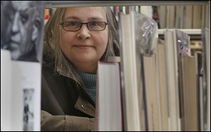 Bowling Green resident Barb Bertonaschi poses with books at the Wood County Library in Bowling Green. It’s been seven years since the 59-year-old woman had a paycheck. She’s trying to take classes at Owens Community College, but education is expensive.