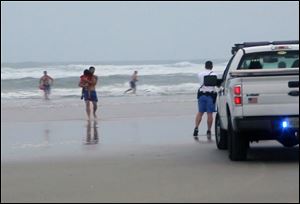 A lifeguard carries one of the three children rescued from a minivan that their mother, Ebony Wilkerson, drove into the Atlantic in Daytona Beach, Fla.