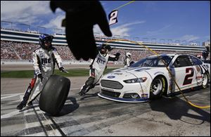 A pit crew member reaches to grab one of the used tires off of Brad Keselowski's car during a pit stop at a NASCAR Sprint Cup Series race on Sunday in Las Vegas.