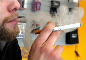 A sales associate demonstrates the use of a electronic cigarette and the smoke like vapor that comes from it in Aurora, Colo.