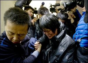 A Chinese relative of passengers aboard a missing Malaysia Airlines plane cries as she leaves a hotel room for relatives or friends of passengers aboard the missing airplane on Sunday in Beijing.