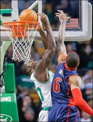 The Celtics’ Brandon Bass, left, scores on a reverse dunk in front of the Pistons’ Josh Smith during the first quarter on Sunday.