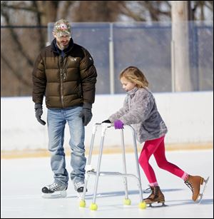 Dave Mack of Ottawa Hills watches as his daughter Emily Mack, 7, uses a walker to learn how to skate during an afternoon at the Ottawa Park ice rink. The season ended at the rink in West Toledo on Sunday.