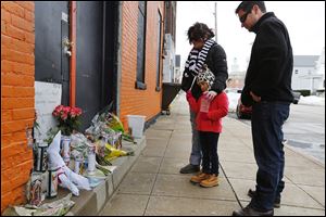 Dalena Buchman, her daughter, Kyla, 5, and her husband, Jeff, visit a memorial at the Last Call Bar on North Park Avenue in Fremont. The Buchmans live in Fremont; Jeff Buchman is the cousin of Ramiro Sanchez, 28, a bartender at the Last Call who was killed on the job early Sunday.