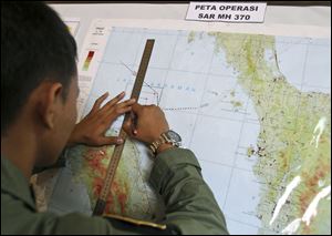 An Indonesian Air Force officer draws a flight pattern flown earlier in a search operation for the missing Malaysia Airlines Boeing 777, during a post-mission briefing at Suwondo air base in Medan, North Sumatra, Indonesia today.