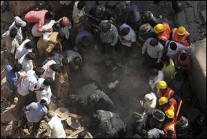 Rescue workers search for survivors in the debris of a building that collapsed Friday in Mumbai, India.