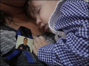 Emmitt Chavez, 16 months, sleeps near a photo of his father, Jose ‘Andy’ Chavez, during the funeral service.