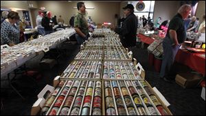 Rob Reichenbach, center left in camo shirt, speaks to a potential customer during the 40th Annual Buckeye Beer and Mancave Show at the UAW Hall in Toledo. Reichenbach, who brought 2,000 of his 35,000 beer cans to trade and sell, said he has been to this show 29 times.