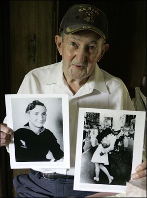 Glenn McDuffie holds a portrait of himself as a young man, left, and a copy of Alfred Eisenstaedt's iconic Life magazine shot of a sailor embracing a nurse in a white uniform, right, at his Houston home in this 2007 file photo.