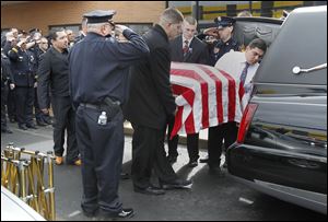Police salute as family members place the coffin of Jose ‘Andy’ Chavez into the hearse at Woodmore High School. Scores of law enforcement workers and firefighters attended the rite. 