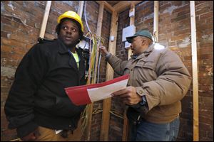 Montana Dean, 24, of Toledo, left, listens as electrical contractor Brady Jackson, right, talks about electrical wires during the renovation project for United Toledo YouthBuild.