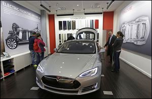 Customers check out a new Tesla all electric car, today, at a Tesla showroom inside the Kenwood Towne Centre in Cincinnati. 