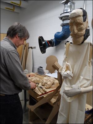 Bradford Clark works on the faces of  townspeople puppets for ‘Frankenstein.’ At right is the Victor Frankenstein puppet in a preliminary stage.
