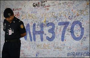 Malaysia airport police officer stands in front of  messages board for the passengers aboard a missing Malaysia Airlines plane at Kuala Lumpur International Airport in Sepang, Malaysia, today.