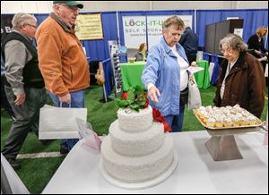 Holland residents Dubby Ruckman, second from right, and Ada Mae Schooner, right, admire a three-tier wedding cake from Eston’s Bakery during the Showcase Sylvania Expo at Tam-O-Shanter.