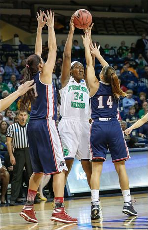 Notre Dame’s Markisha Wright passes over the arms of Robert Morris’ Artemis Spanou, left, and Ashley Ravelli at Savage Arena.
