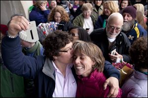 Elizabeth Patten, left, holds up the first marriage ticket to marry her partner Johnnie Terry today in front of the Washtenaw County Clerks office in Ann Arbor, Mich.