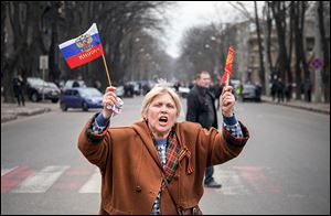 A pro-Russian activist waves Russian and former Soviet flags with a ribbon symbolizing the Soviet victory in WWII, during a rally against usurpation of power and political repression.