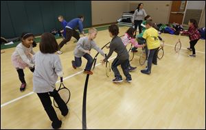Students race to catch spinning rackets during Tennis Club at Central Trail Elementary School in Sylvania Township. The club meets Tuesday and Thursday at Central Trail and Monday and Wednesday at Highland. No one sits on the sidelines, said volunteer Brian Meyer.