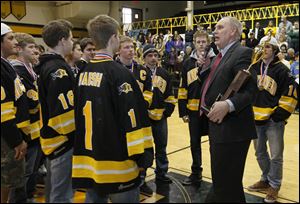Jerry Snodgrass of the Ohio High School Athletic Association holds the trophy while addressing the crowd in Northview’s gym as the seniors on the hockey team look on.