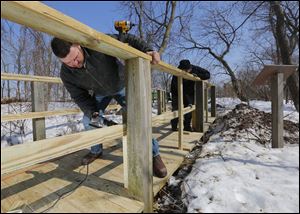Todd Ebersole, left, and Brian Pritchard, both of Todd Hunt Contracting, Marion, Ohio, install a new railing on the boardwalk at Magee Marsh near Oak Harbor, Ohio. The 25-year-old boardwalk’s deteriorating condition makes the structure a safety hazard, the Friends of Magee Marsh said.