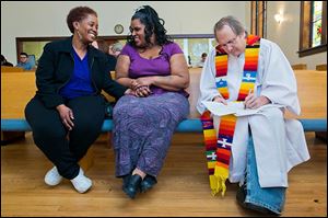 Renecia Hall, left, and Kristen Martin wait for their marriage license from the Rev. Bill Freeman at their wedding ceremony at Harbor Unitarian Universalist Church in Muskegon, Mich.