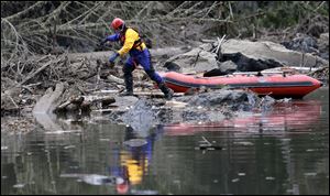 A searcher steps off of his boat to look through debris.
