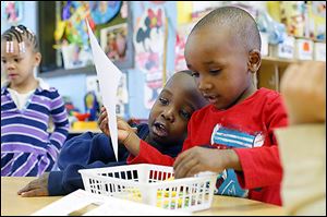 Regal Ellis, 4, and Jailan Moore, 3, right, help each other with their writing exercise during an afternoon Head Start class at the Frederick Douglass Community Center.