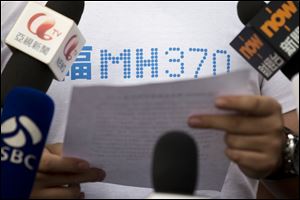 A representative of relatives of Chinese passengers onboard Malaysia Airlines Flight 370, center, makes an announcement to journalists prior to a briefing with Malaysian officials at a hotel in Beijing, China. About two-thirds of the missing, 239 people onboard, are Chinese, and their relatives have lashed out at Malaysia for essentially declaring their family members dead without any physical evidence of the plane's remains. 