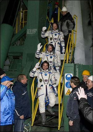 Expedition 39 Soyuz commander Aleksander Skvortsov, of the Russian Federal Space Agency (Roscosmos), followed by, flight engineer Steve Swanson of NASA, middle, and flight engineer Oleg Artemyev of Roscosmos, wave farewell prior to boarding the Soyuz rocket today.