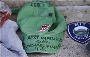A baseball cap with a written tribute to fallen Boston firefighter Michael Kennedy rests at a makeshift memorial in front of fire station Engine 33, Thursday. Fire station Engine 33 was the station of fallen firefighters Kennedy and Lt. Edward Walsh and who lost their lives fighting a 9-alarm fire Wednesday.
