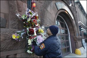 Somerville, Mass. firefighter Earl Johnson places flowers at a makeshift memorial on the front of fire station Engine 33, today in Boston.