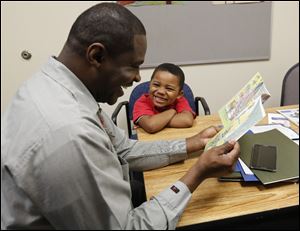 David Bush, from the Toledo-Lucas County Public Library, helps Devin Burke read ‘The Boy Who Wouldn’t Share’ as part of the Real Men READ-y program, which gives black boys a role model.