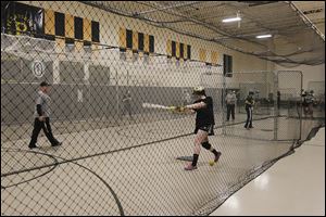 Megan Rufty, 16, a junior, takes batting practice inside the Perrysburg High School gym instead of out on the diamond. Because of weather, the team has had only one brief outdoor practice.