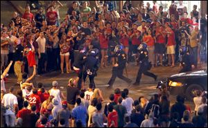 Tucson Police Officers rush out of their line to take a man into custody who had been taunting them and riling up a crowd of fans in Maingate Square, Saturday in Tucson Ariz. following Arizona's loss to Wisconsin 64-63 in the West Region NCAA final.