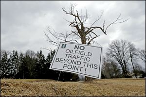 A sign near a gas well drilling site is visible near a road in Pulaski, Pa. 