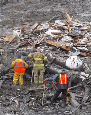 Searchers pause for a moment of silence at the scene of a deadly mudslide Saturday in Oso, Wash. Besides the more than two dozen bodies already found, many more people could be buried in the debris pile left from the mudslide one week ago.