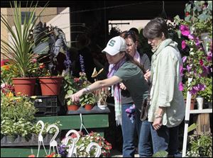 Devon Barrett, pointing, with Jennie Buechele, center, and her mom, Judie Barrett, all from Ottawa Lake, Mich., attend last year's Flower Day weekend at the Erie Street Market.