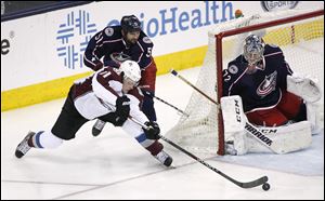 Columbus Blue Jackets' Fedor Tyutin (51) pushes Colorado Avalanche's Jamie McGinn (11) from behind as he tries to score on goalie Sergei Bobrovsky during the third period.
